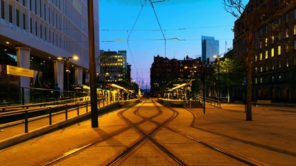 Sticker - Manchester, England. Light rail yellow tram in city center of Manchester, UK in the evening. Time-lapse from day to night with illumination