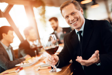 Meeting with chinese businessmen in restaurant. Man is posing with wine glass.