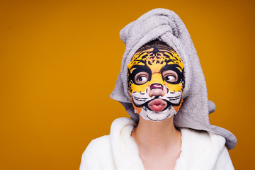 Wall Mural - funny young girl with a towel on her head after a shower, face mask with an animal's muzzle, facial