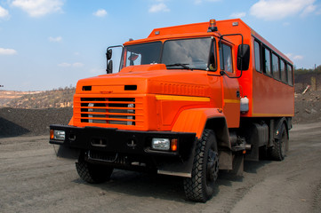 Wall Mural - Orange car to transport workers in the ore quarry to workplaces. Ukrainian truck.