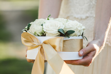 Wall Mural - Rose box. Beautiful roses in white gift box with golden bow. Bride holding flower decoration on wedding day.