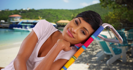 Wall Mural - Lovely black female relaxing on Caribbean beach smiling at camera joyfully 