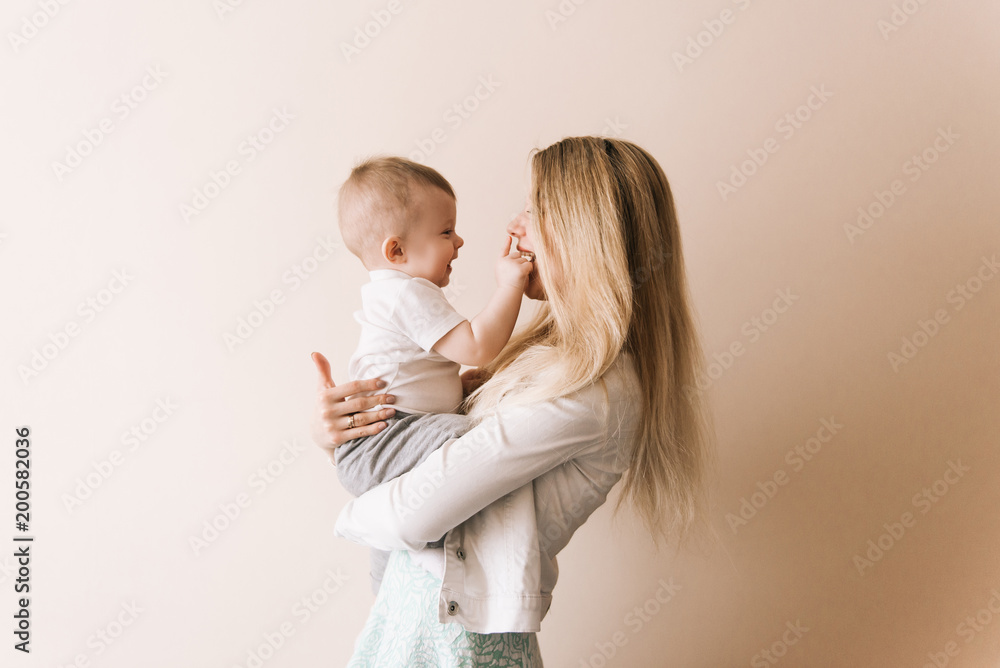 Mother playing with baby boy, happy family having fun indoor, cheerful sweet kid portrait, mom and child, healthy toddler, lifting throwing carrying holding up game - obrazy, fototapety, plakaty 