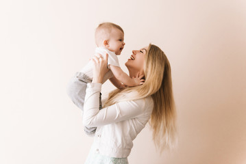 you are my treasure! cheerful beautiful young woman holding baby boy in her hands and looking at him