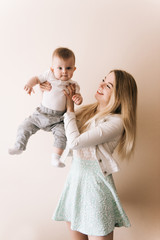 You are my treasure! cheerful beautiful young woman holding baby boy in her hands and looking at him with love  at home