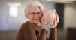 © Mark Adams - Caucasian elder woman holding piggy bank posing happily for camera indoors