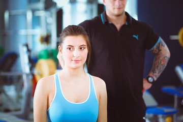 Wall Mural - Beautiful woman at the gym exercising with her trainer. Beautiful woman. Gym