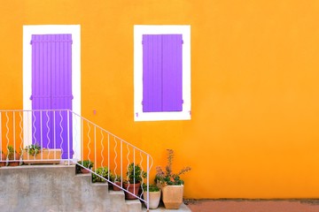 Vibrant yellow house front with purple shuttered door and window, Provence, France. Copy space.