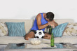 young attractive soccer fan and supporter man at home sofa couch watching football game on TV dejected and sad after team defeat loss and defeat