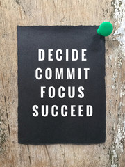 Motivational and inspirational quote - ‘Decide, commit, focus and succeed’ written on black paper. With vintage-styled background.