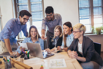 Wall Mural -  Group of young business people in smart casual wear working together in creative office using laptop.