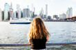 Back of young woman outside outdoors in NYC New York City Brooklyn Bridge Park by east river, railing, looking at view of cityscape skyline travel