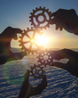 © gerasimov174 - four people businessman hold gears puzzle on sunset background. coherence in work, business concept idea, cooperation, teamwork, strategy.