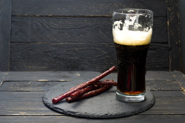 A half-empty glass of beer. Dark beer and sausages.