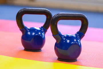 a set of two blue kettle bells sitting on colourful exercise mats.