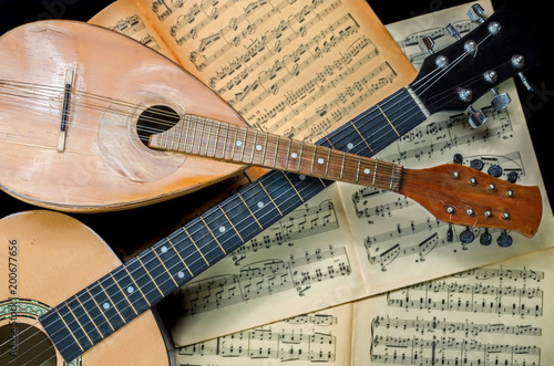 Obraz Dibond Mandolin and guitar with blurred sheet music books in the background. Stringed musical instruments.