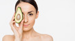 Avocado for a healthy body. A beautiful young girl holds half the avocados in her hands and points to the camera.