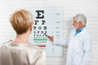 © serhiibobyk - Photo of old ophthalmologist is cheking patient's vision. Doctor working in medical laboratory near table for vision cheking. Wearing white medical uniform. Looking expirienced and skilled.