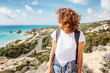 Beautiful young woman traveler with flying hair on a beautiful backdrop of beautiful scenery with blue sea and mountains