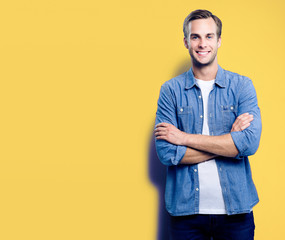 Wall Mural - Portrait of young man standing in crossed arms pose