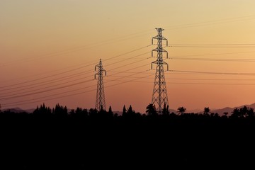 High voltage post or  tower in field silhouette in sunset background, Orange sky