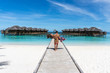Honeymoon on Maldives. Man holding his wife on arms on bridge on ocean beach