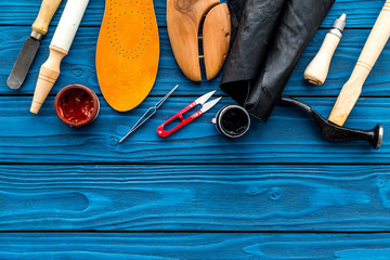 Wall Mural - Instruments and materials for make shoes. Shoemaker's work desk. Hummer, awl, knife, sciccors, wooden shoe, insole, paint and leather. Blue wooden background top view copy space