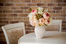Decoration Artificial Peonies Flower In The Vase On The White Table With Brick Background.