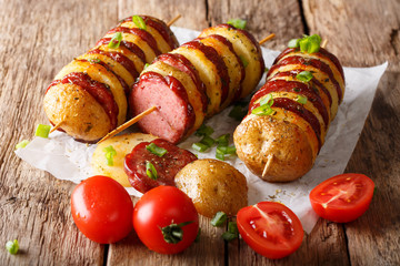 Freshly prepared shish kebab from potato skewers with sausage salami and tomatoes, green onions. horizontal