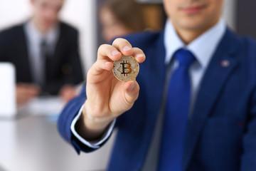 Businessman holding golden bitcoin and smiling. Virtual anonymous money concept, success in digital finance