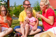© Kzenon - Happy family having picnic in garden front of their home