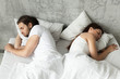 Unhappy indifferent couple sleeping separately back to back keeping distance lying in bed at home, married man and woman ignoring each other avoiding sex, having conflict or sexual problems concept