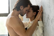 © fizkes - Beautiful young sensual couple holding hands leaning on wall, loving millennial affectionate  man and woman getting closer to kiss each other teasing enjoying tenderness and intimacy, feeling desire