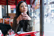 © nenetus - Thoughtful young asian woman drinking coffee in the terrace of a coffee shop.
