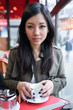 © nenetus - Beautiful young asian woman drinking coffee in the terrace of a coffee shop.