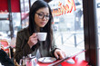 © nenetus - Beautiful young asian woman using her digital tablet while drinking coffee in coffee shop.