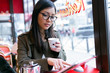© nenetus - Beautiful young asian woman using her digital tablet while drinking coffee in coffee shop.