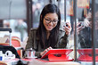 © nenetus - Beautiful young asian woman using her digital tablet while drinking coffee in coffee shop.