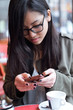 © nenetus - Beautiful young asian woman using her mobile phone in the terrace of a coffee shop.