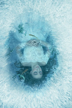 Story Of Sleeping Beauty. Girl Is Sleeping On Bottom Of Frozen Lake, Fish Seaweed Are Swimming. Everything Is Covered With Ice Frost. Underwater Photography. Art Image Fantasy Woman Princess