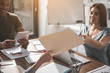 © Yakobchuk Olena - Satisfied man and women sitting at the table in meeting room. Focus on female hands passing each other folder with papers