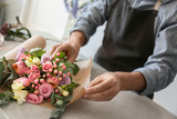 Fototapeta Morze - Male florist creating beautiful bouquet at table, closeup
