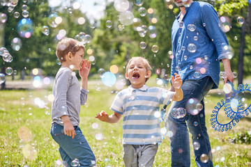 Wall Mural - portrait shot of cute little boy trying to catch soap bubbles with his mouth while having childrens 