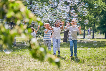 Wall Mural - cute little children with wide smiles on their faces running towards camera and trying to catch colo