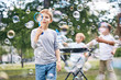 © Seventyfour - Group of little boys wrapped up in blowing colorful soap bubbles while gathered together at green public park