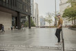 © Travis - Man waiting in plaza in large city