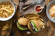Top view outdoor table with burger, french fries and salad on wooden table, top view