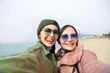 © ClaudiK - Mother and adult daughter are doing selfie on the beach going crazy and showing tongueSunset light.Happy and positive emotions.Hipster family.Parents and teenagers.Summer vacation self-portrait