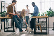 © LIGHTFIELD STUDIOS - multicultural business colleagues with textbooks and jack russel terrier on leash in modern office