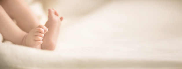 Wall Mural - newborn baby feet on creamy blanket. mom and her child. maternity, family, birth concept. copy space